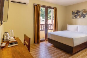 A hotel room with a bed, a wooden desk with a coffee maker, a chair, and a sliding glass door to an outdoor area. - Serene La Playa (Malay)