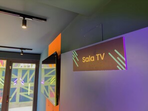 Seinässä on kyltti, jossa lukee ”Sala TV”, katossa on valaisin ja ikkunassa on geometrinen kuvio.