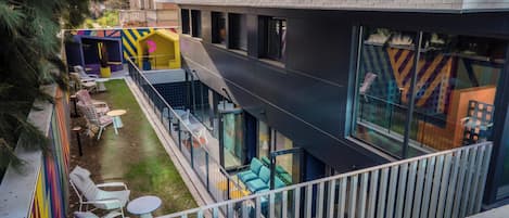 Ein modernes Gebäude mit flachem Dach, großen Fenstern und einem Balkon mit Sitzgelegenheit im Freien.