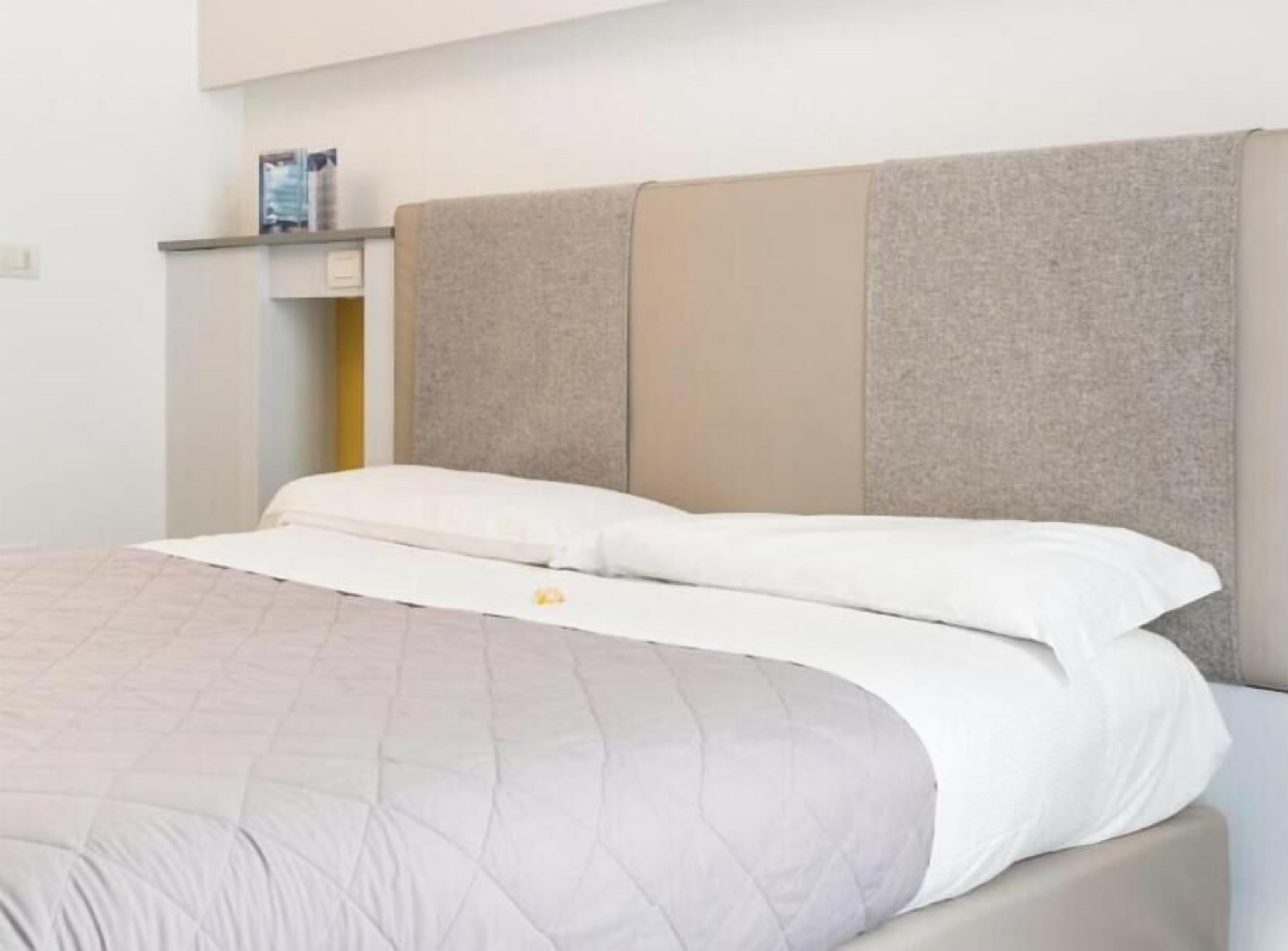 Uma cama com cabeceira, mesa de cabeceira e prateleira na parede.