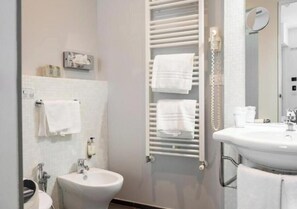 Un baño con bidé, lavabo y un perchero para toallas.