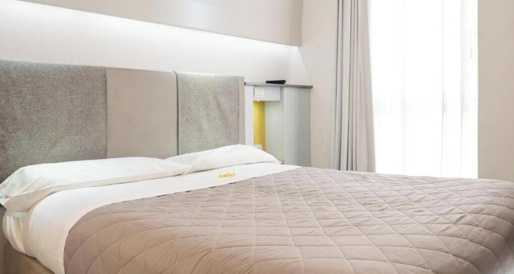 Une chambre d’hôtel avec un lit, une table de chevet et une lampe.
