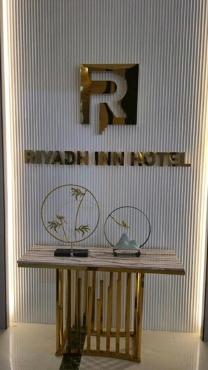 A reception desk with a plaque reading 'RIYADH INN HOTEL' and a large letter 'R' above it. - Riyadh Inn Hotel (Riyadh)