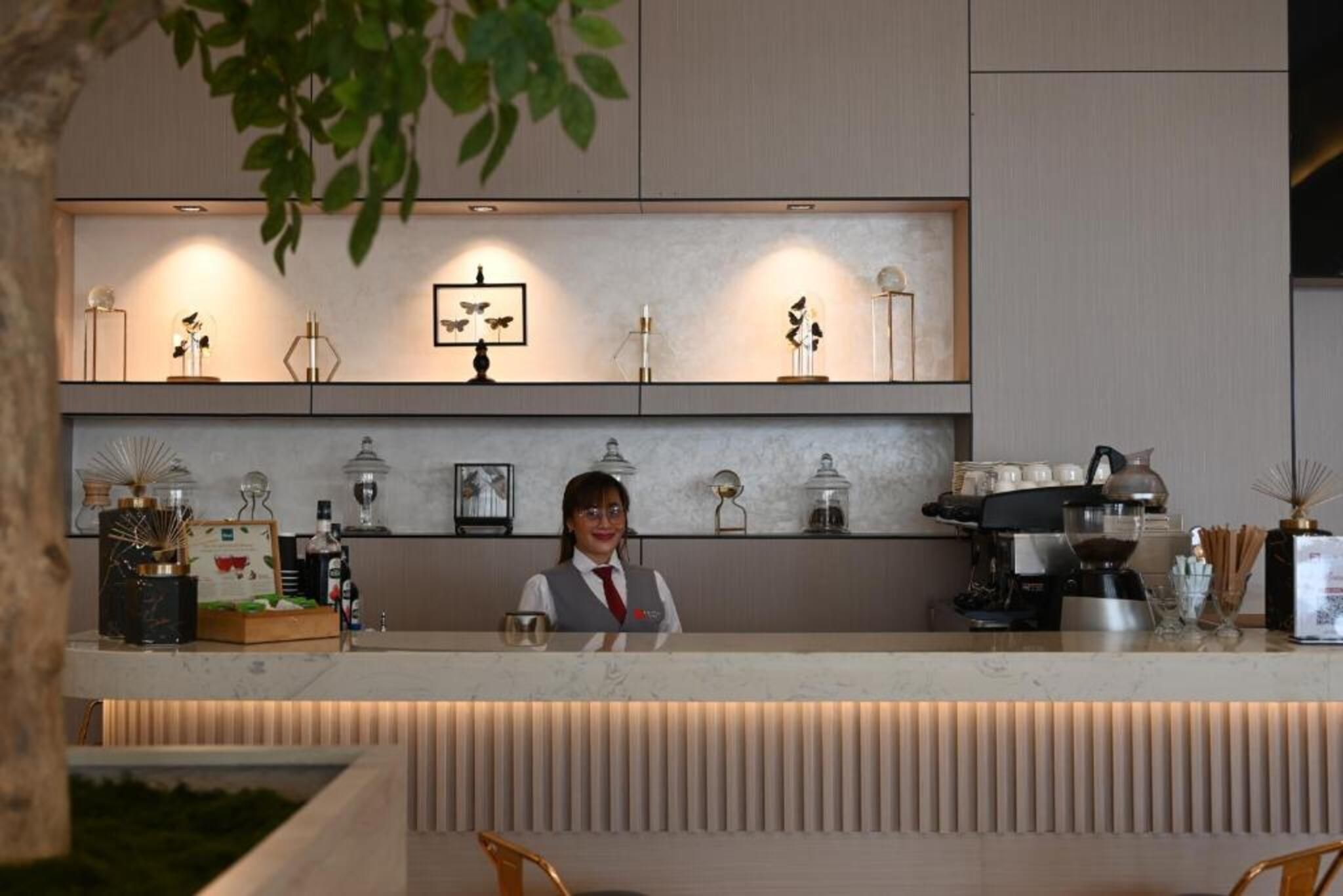 A reception desk with a barista, a coffee machine, and various decorative items on shelves.