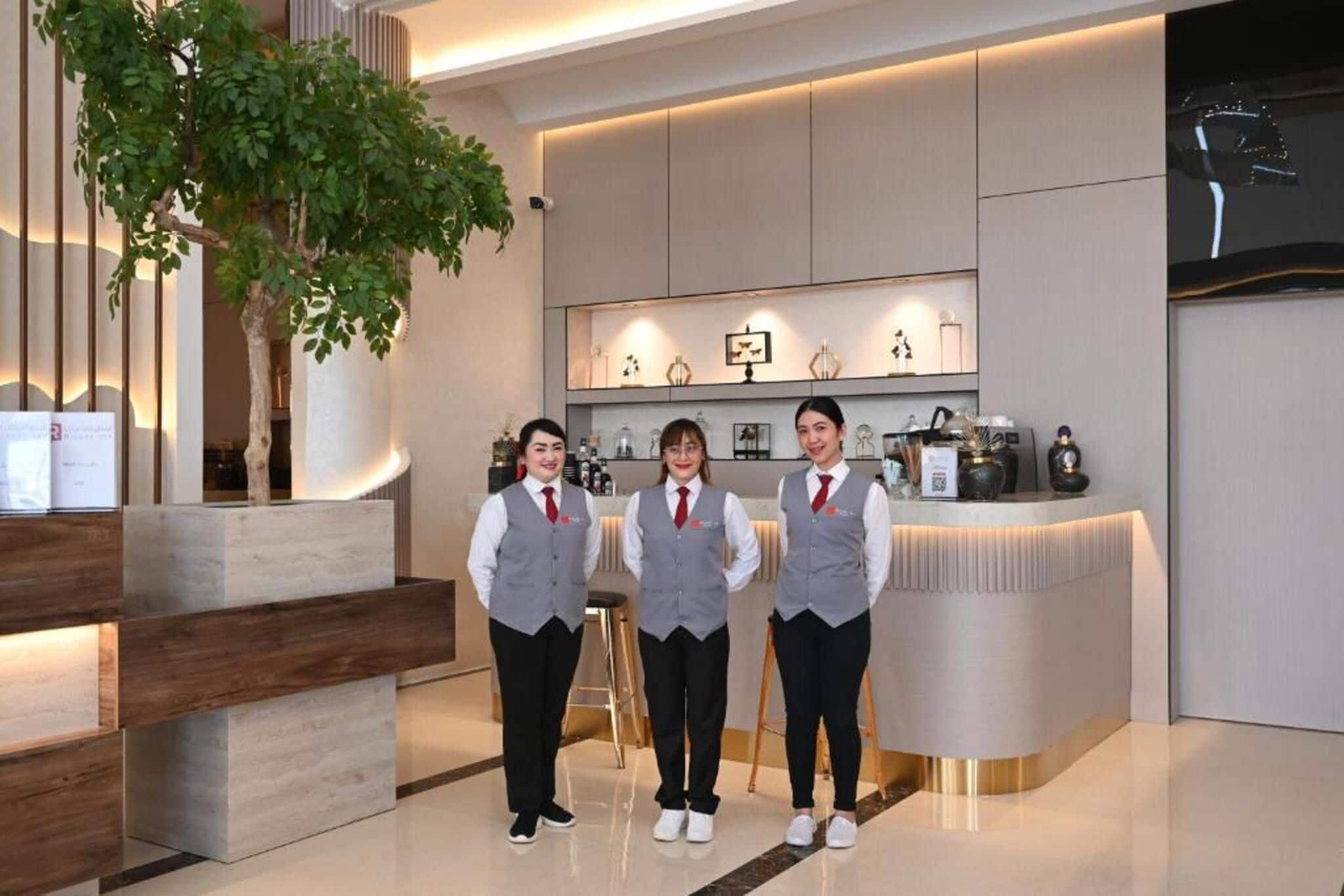 A reception area with a modern design, featuring a reception desk, a large potted plant, and a wall-mounted display with various items.