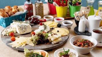 Una tabla de quesos con diferentes tipos de queso, frutas y nueces, acompañada de recipientes pequeños con salsas y condimentos.