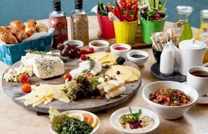 Un plat de formatges amb diverses varietats, fruita i fruits secs, acompanyat de petits recipients amb salses i condiments.
