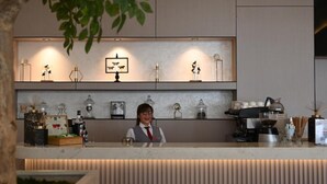 A reception desk with a barista, a coffee machine, and various decorative items on shelves. - Riyadh Inn Hotel (Riyadh)