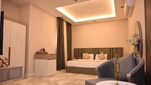 A modern hotel room with a bed, a seating area with a table, a wardrobe, and a mirror. - Riyadh Inn Hotel (Riyadh)