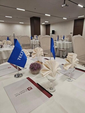 A conference room with tables set for a meeting, featuring nameplates, tablecloths, and a projector. - Riyadh Inn Hotel (Riyadh)