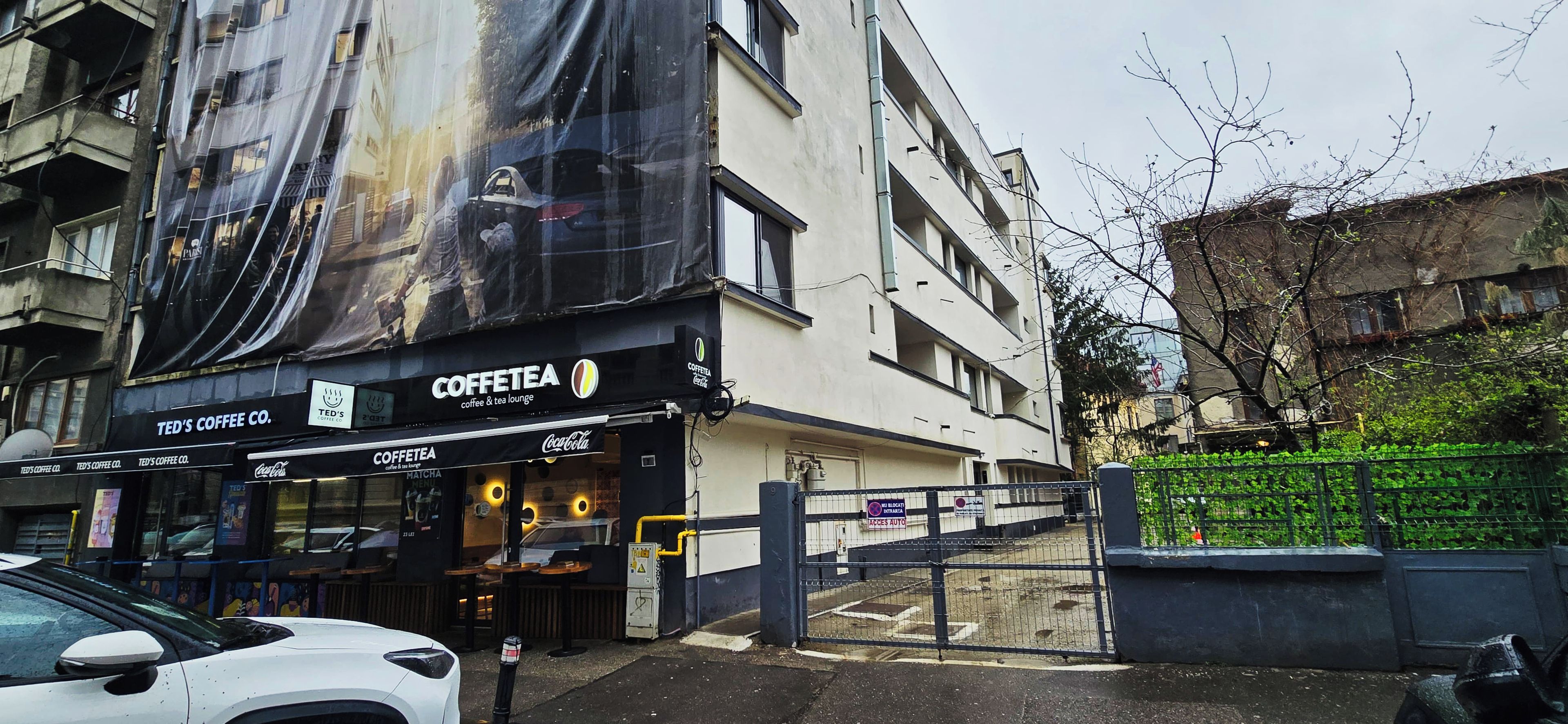 A building with a large coffee shop named 'COFFEE TEA' on the ground floor, featuring a Coca-Cola sign.