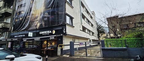 A building with a large coffee shop named 'COFFEE TEA' on the ground floor, featuring a Coca-Cola sign.