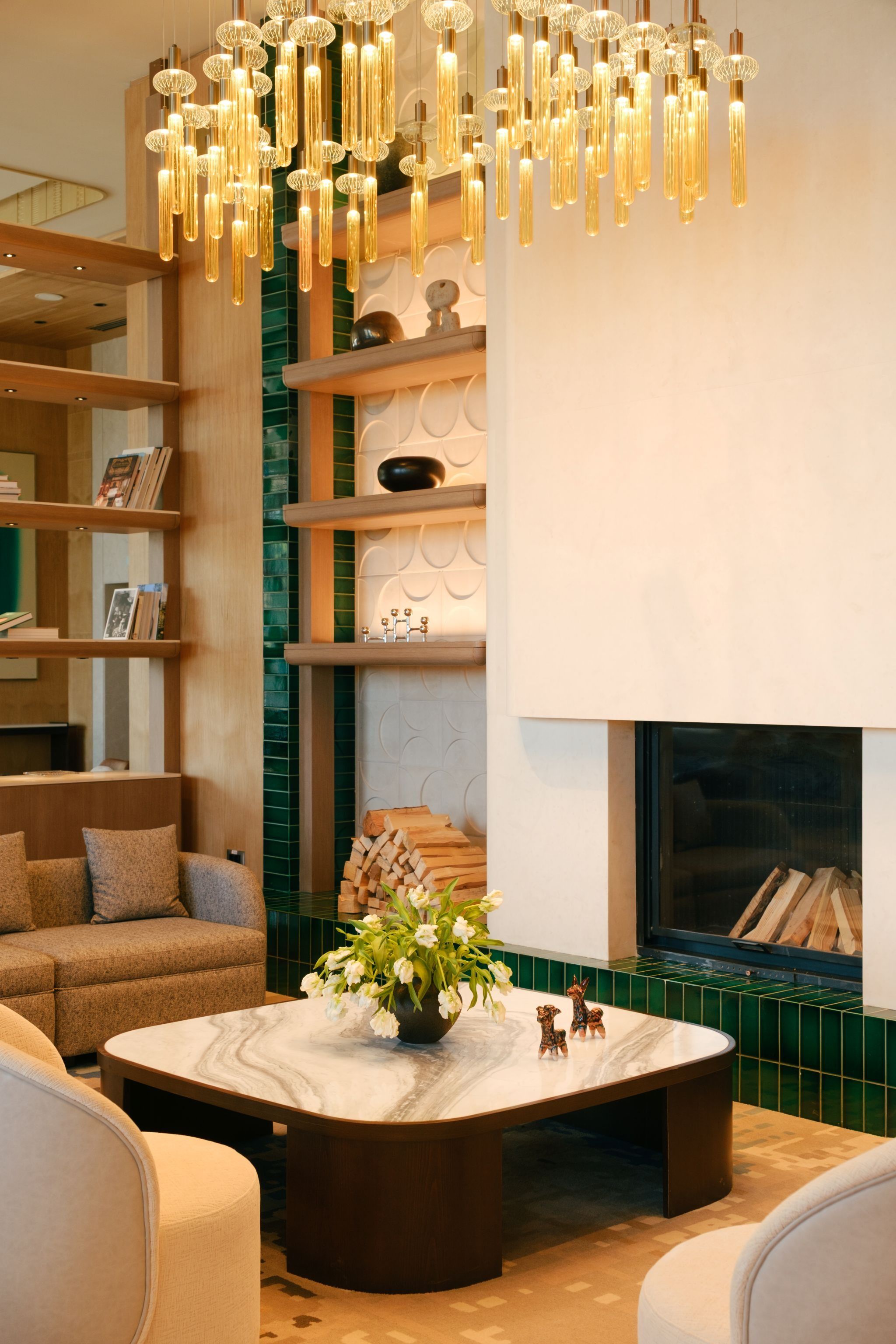 A modern living room with a fireplace, a marble coffee table, and a hanging light fixture.