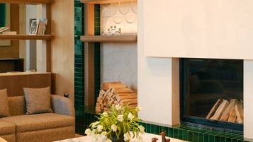 A modern living room with a fireplace, a marble coffee table, and a hanging light fixture.