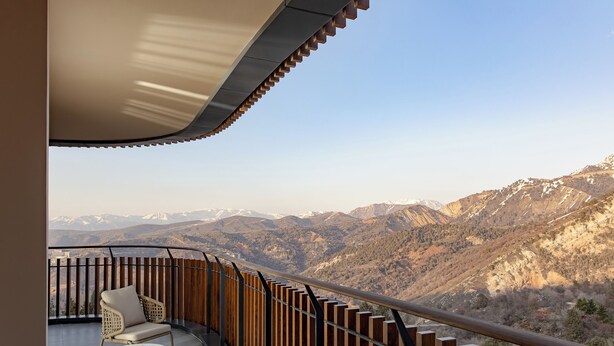 A balcony with a view of mountains, a chair, and a table. - Beldersoy Resort And Spa (Tashkent)