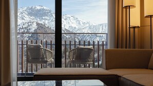 A room with a view of snow-covered mountains, a sofa, two wicker chairs, and a floor lamp. - Beldersoy Resort And Spa (Tashkent)