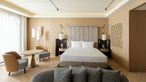 A modern hotel room with a large bed, two bedside tables, a sofa, and a small round table. - Beldersoy Resort And Spa (Tashkent)