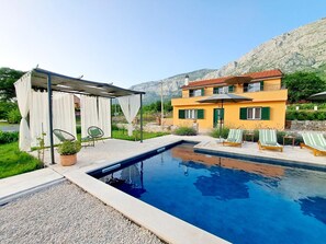 Una piscina al aire libre, sombrillas, sillones reclinables de piscina