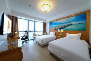 A hotel room with two beds, a desk, a chair, a television, and a large painting of a pier. - Royal J Hotel (Cebu City)