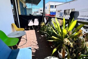 A balcony with seating, potted plants, and a view of the cityscape. - C YOU Rooms (Semporna)