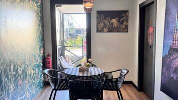 A dining area with a table and chairs, a hanging light fixture, and a door leading to an outdoor space.