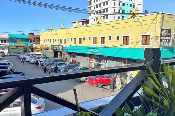Un hotel con toldo verde, un letrero visible que dice 'SIPADIN INN 1' y un estacionamiento con varios autos.