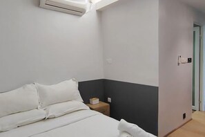 Un dormitorio con cama, mesita de noche y equipo de aire acondicionado.