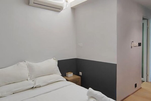 A bedroom with a bed, a nightstand, and an air conditioning unit. - C YOU Rooms (Semporna)