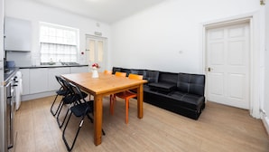 Una cocina moderna con una mesa de comedor y sillas, un sofá de cuero negro y una puerta blanca.