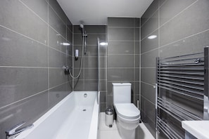 Ein modernes Badezimmer mit Badewanne, Toilette und Dusche.