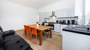 Una cocina moderna con armarios blancos, una mesa de comedor de madera y sillas color naranja.
