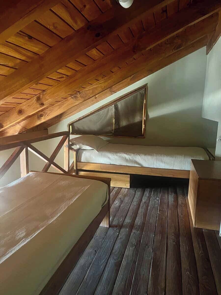 Dormitorio tipo loft con techo de madera, litera y un pequeño escritorio.