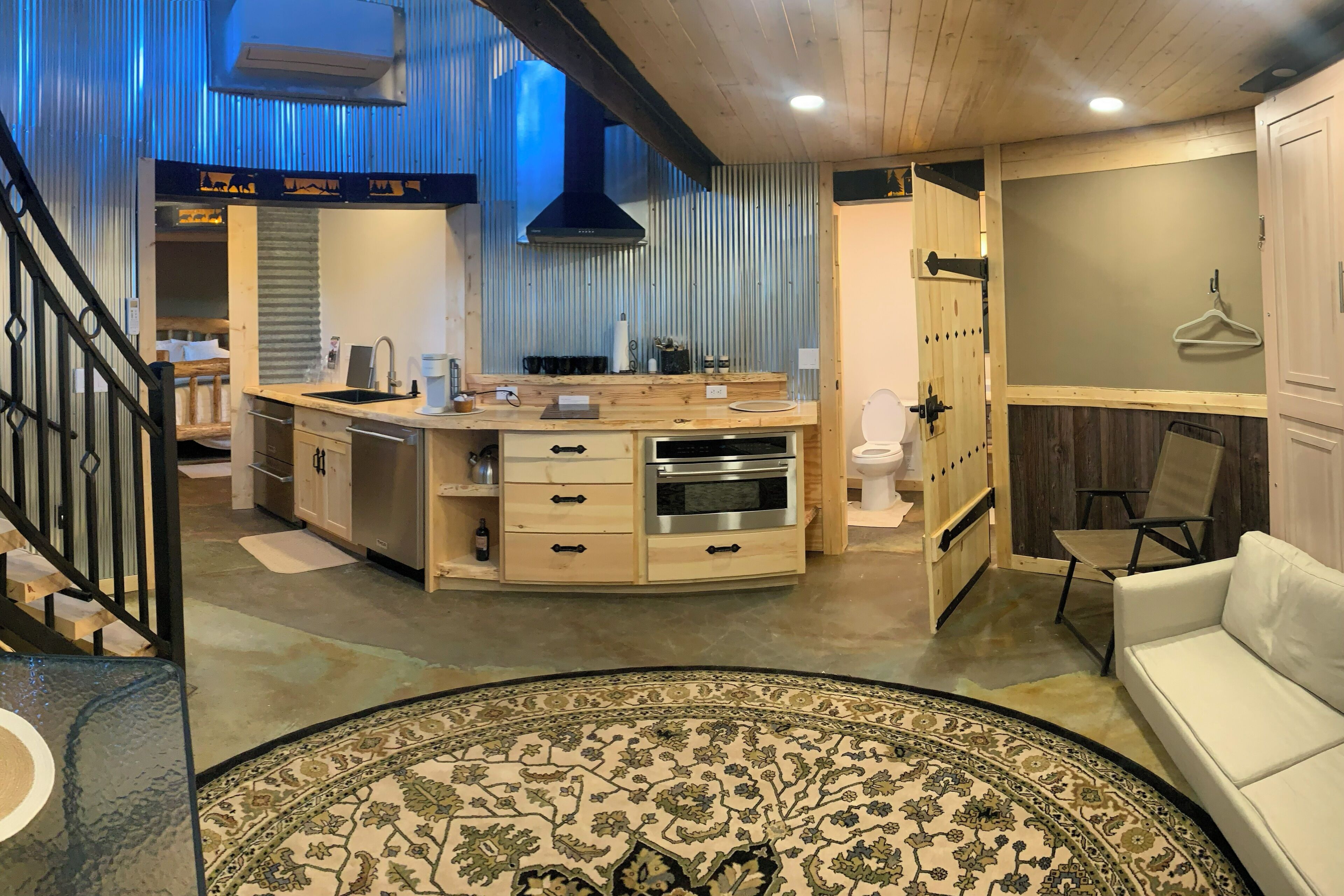 A modern kitchen with a central island, wooden cabinets, and a stainless steel oven.