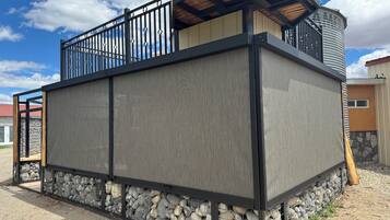 A building with a stone foundation, a metal fence, and a wooden deck.