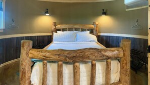 Una cama con cabecera de madera, dos lámparas de pared y un colgante.