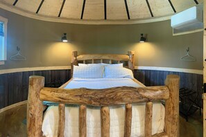 Un lit avec une tĂȘte de lit en bois, deux lampes fixĂ©es au mur et un luminaire suspendu.