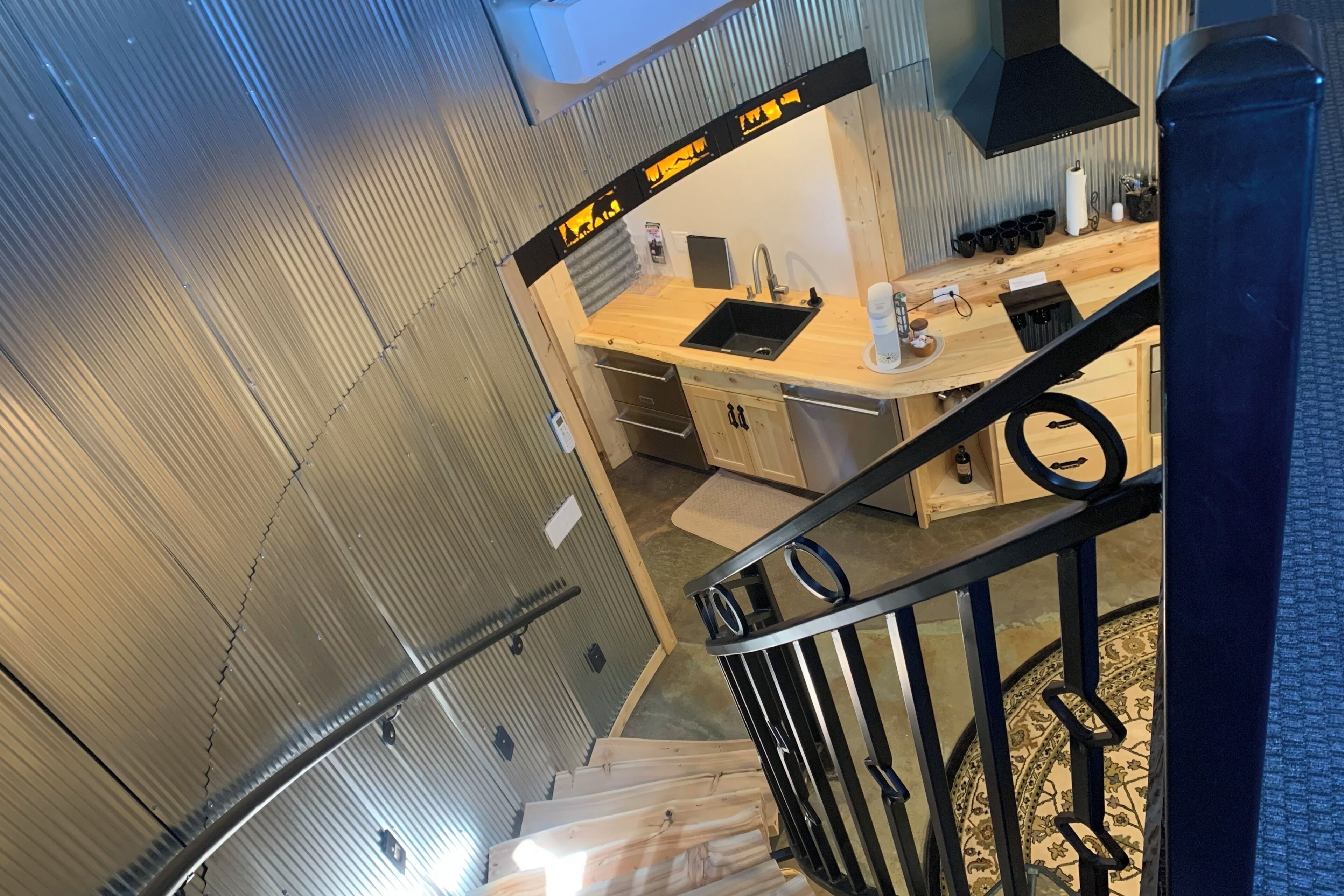 Una cocina moderna con encimera de madera, pileta negra y electrodomésticos de acero inoxidable.