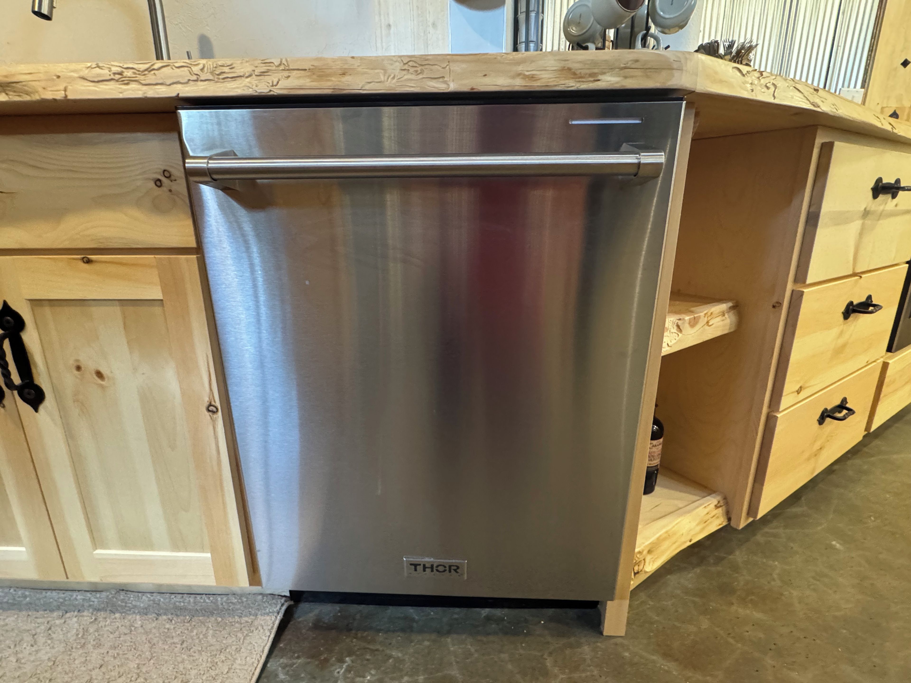 A stainless steel dishwasher in a kitchen with wooden cabinetry and a countertop.