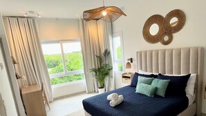 Ein modernes Schlafzimmer mit einem großen Bett, Blick ins Grüne und einer einzigartigen Wanddekoration.