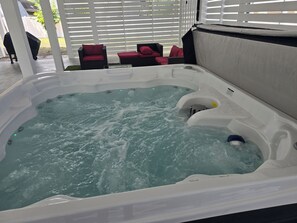 Ein Whirlpool mit Wasser, umgeben von Gartenmöbeln und einem weißen Zaun.