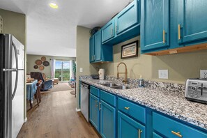A kitchen with teal cabinets, granite countertops, and a stainless steel refrigerator. - The Vista Condo Great Views (Branson)