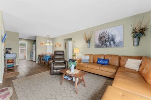 A living room with a sofa, a coffee table, a dining area with chairs, and a kitchen in the background. - The Vista Condo Great Views (Branson)