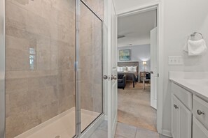 Ein modernes Badezimmer mit Duschkabine aus Glas, einem weißen Waschtisch mit Schubladen und einem Handtuch an einem Handtuchhalter.