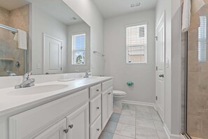 A bathroom with a double sink, toilet, and shower. - The Cloisters at Myrtlewood  4 Bedroom Golf & Family Retreat, (Myrtle Beach)
