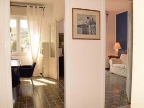Ein Zimmer mit Esstisch, Stühlen, einer weißen Tür, einem gerahmten Bild und einer Lampe.