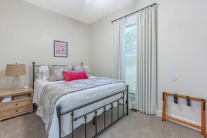 A bedroom with a bed, bedside table, lamp, curtains, and a wall-mounted shelf. - Junction On James!  Historical home with the comfort of modern amenities. (Dayton)