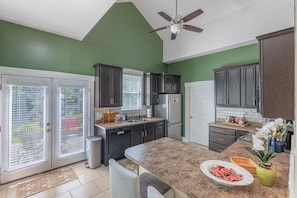 A kitchen with dark cabinets, a granite countertop, a ceiling fan, and a view through a sliding glass door. - Junction On James!  Historical home with the comfort of modern amenities. (Dayton)
