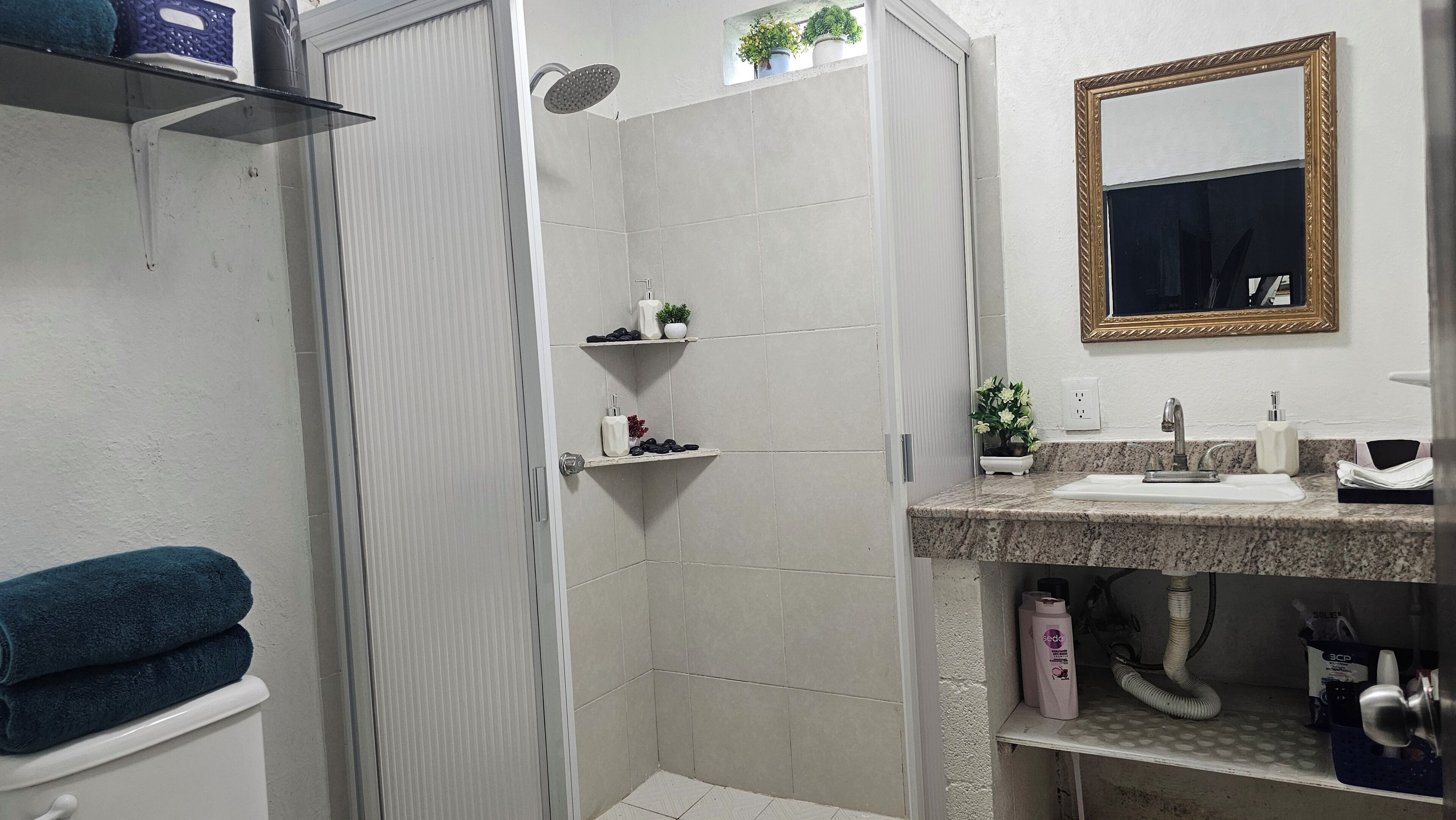 Un baño con ducha, inodoro, lavamanos y espejo.