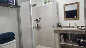 Un baño con ducha, inodoro, lavamanos y espejo.