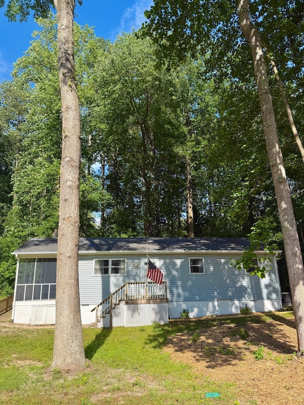 A single-story house with a front porch, a small deck, and an American flag.